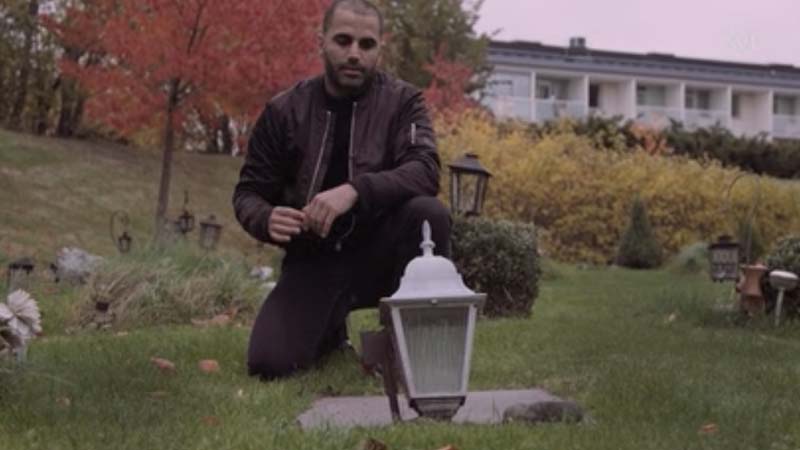 Amir Yaghmai is on his knee near the grave of his friend, Ehsan